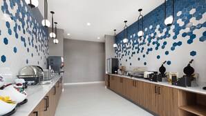 A modern kitchen with a long countertop, wooden cabinets, and a backsplash with blue hexagonal tiles. - La Quinta Inn & Suites by Wyndham Athens I-65 (Athens)