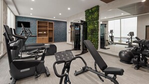 A gym with exercise equipment, a television, and a wall with a blue pattern. - La Quinta Inn & Suites by Wyndham Athens I-65 (Athens)