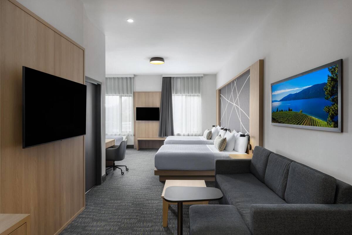Ein Hotelzimmer mit Flachbildfernseher, einer Couch, einem Bett mit Blick, einem Schreibtisch und einem Stuhl.
