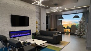 A modern living room with a flat-screen TV, a fireplace, a sofa, and a Christmas tree. - La Quinta Inn & Suites By Wyndham Kelowna Bc (Kelowna)