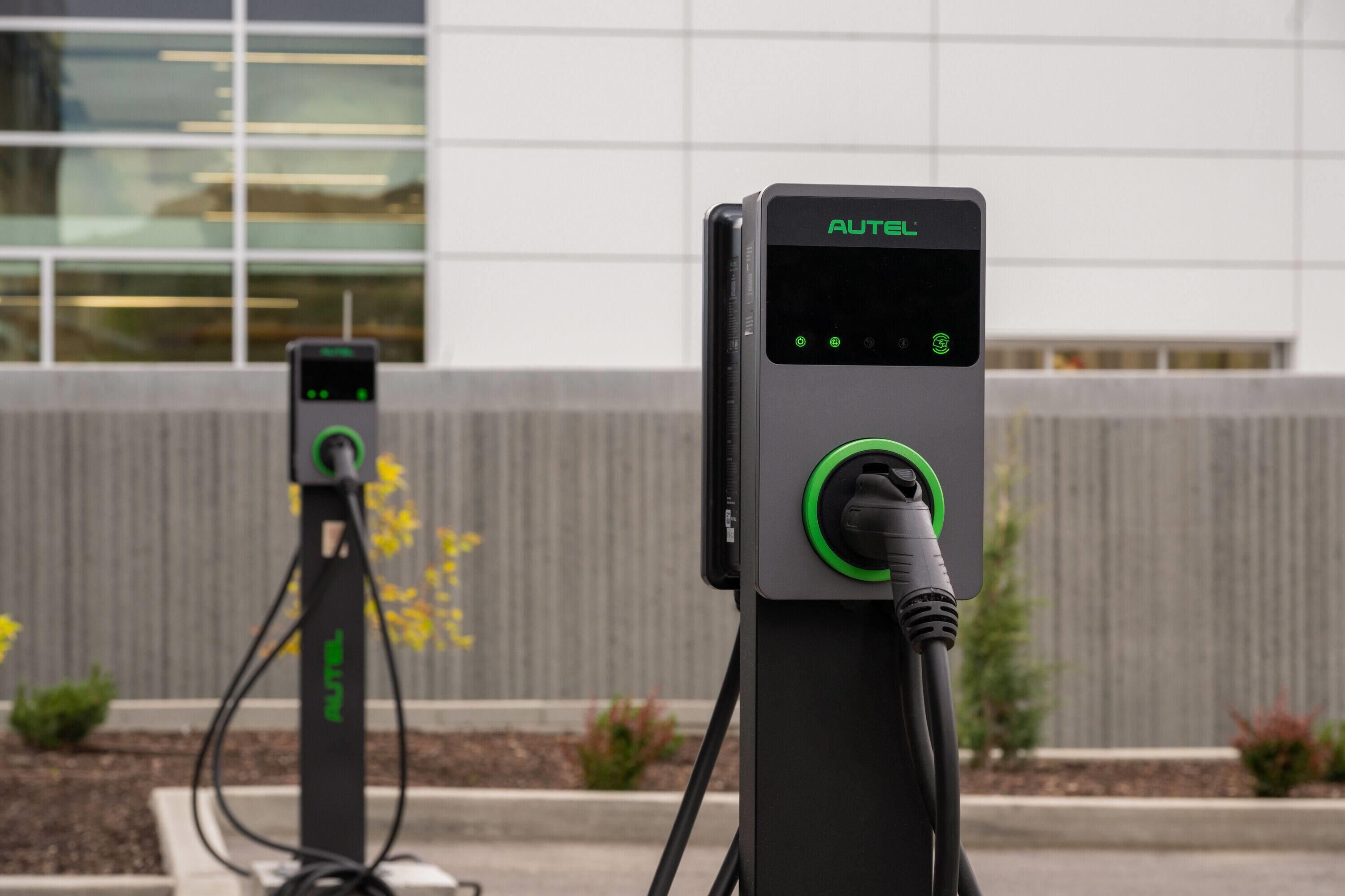 Two electric vehicle charging stations with a modern building in the background.
