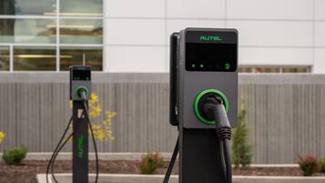 Two electric vehicle charging stations with a modern building in the background.