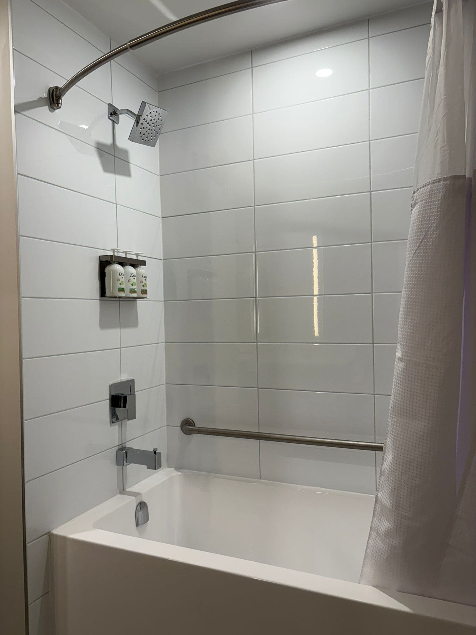 A modern bathroom with a bathtub, a shower, and a hand dryer.