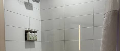 A modern bathroom with a bathtub, a shower, and a hand dryer.