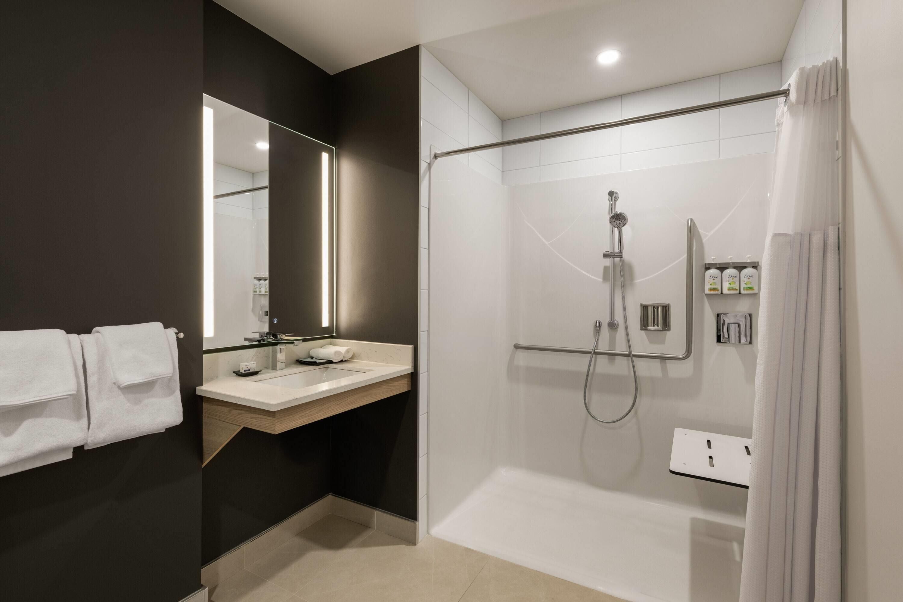 A modern bathroom with a glass-enclosed shower, a vanity with a mirror, and a towel rack.