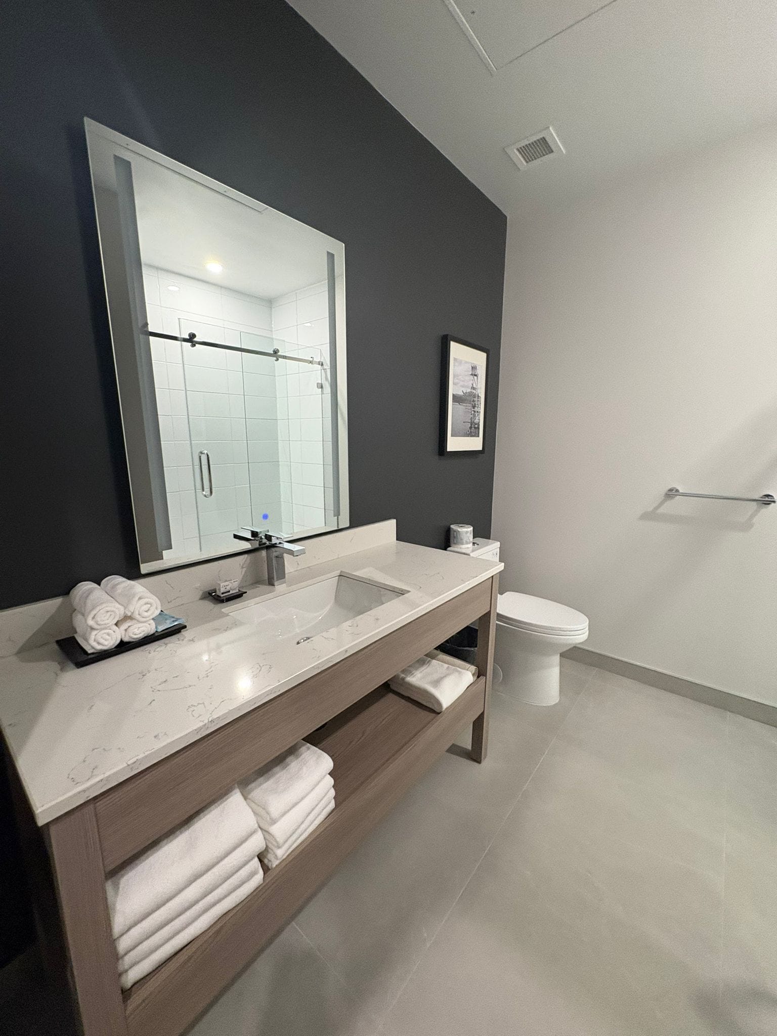 A modern bathroom with a large mirror, a sink, and a toilet.