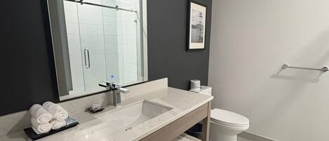 A modern bathroom with a large mirror, a sink, and a toilet.