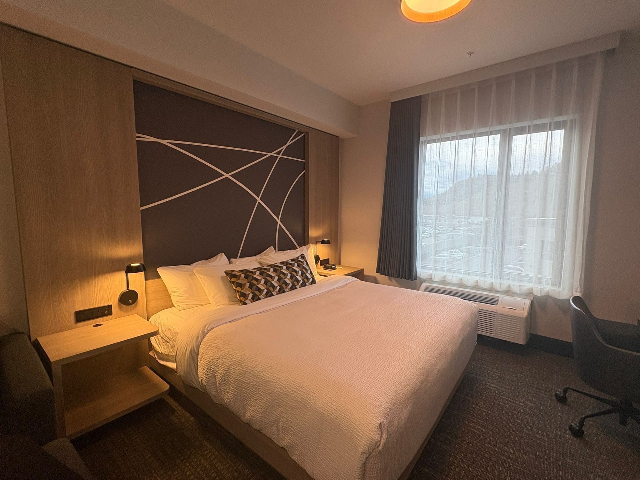 Une chambre d’hôtel avec un grand lit, des tables de chevet, un bureau et une chaise.
