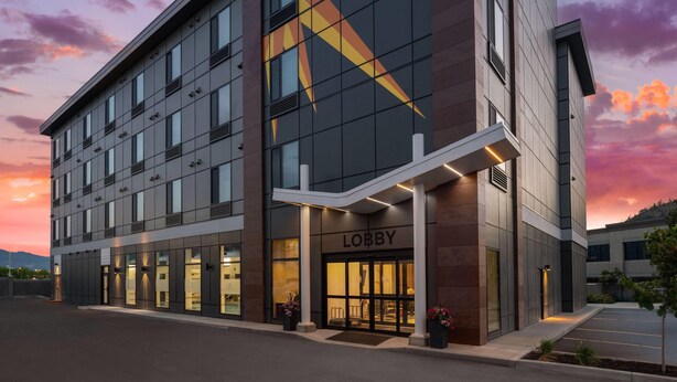 A modern hotel with a prominent lobby entrance, large windows, and a star-shaped design on the facade. - La Quinta Inn & Suites By Wyndham Kelowna Bc (Kelowna)