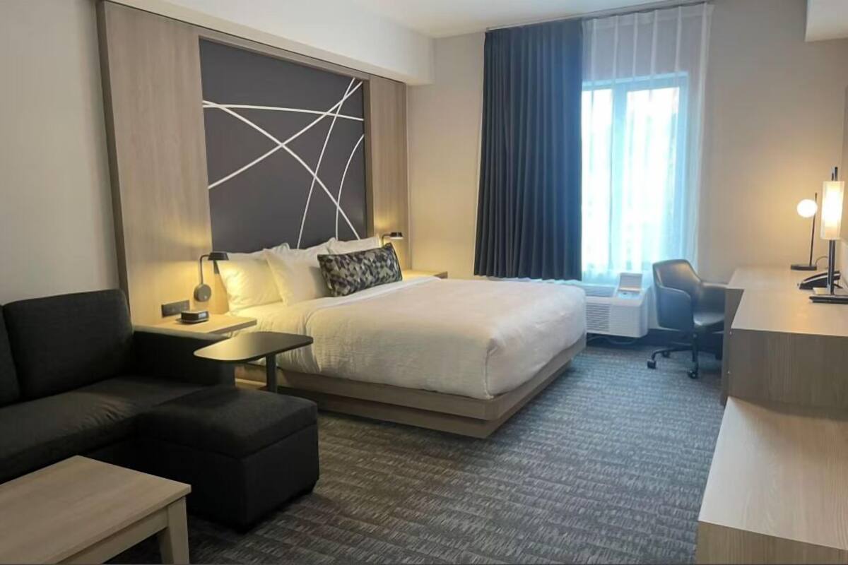 Ein Hotelzimmer mit einem großen Bett, einer Couch, einem Schreibtisch und einem Sessel.