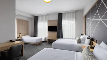 A hotel room with two beds, a desk, a chair, a TV, and a large window with curtains.