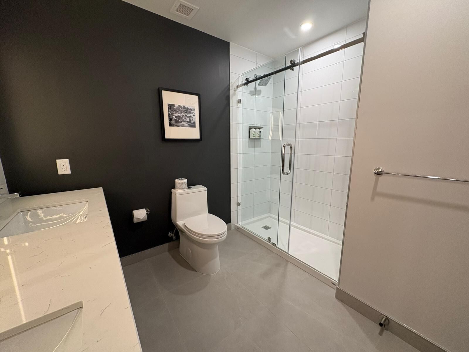 Un baño moderno con cabina de ducha de vidrio, inodoro y tocador de mármol.