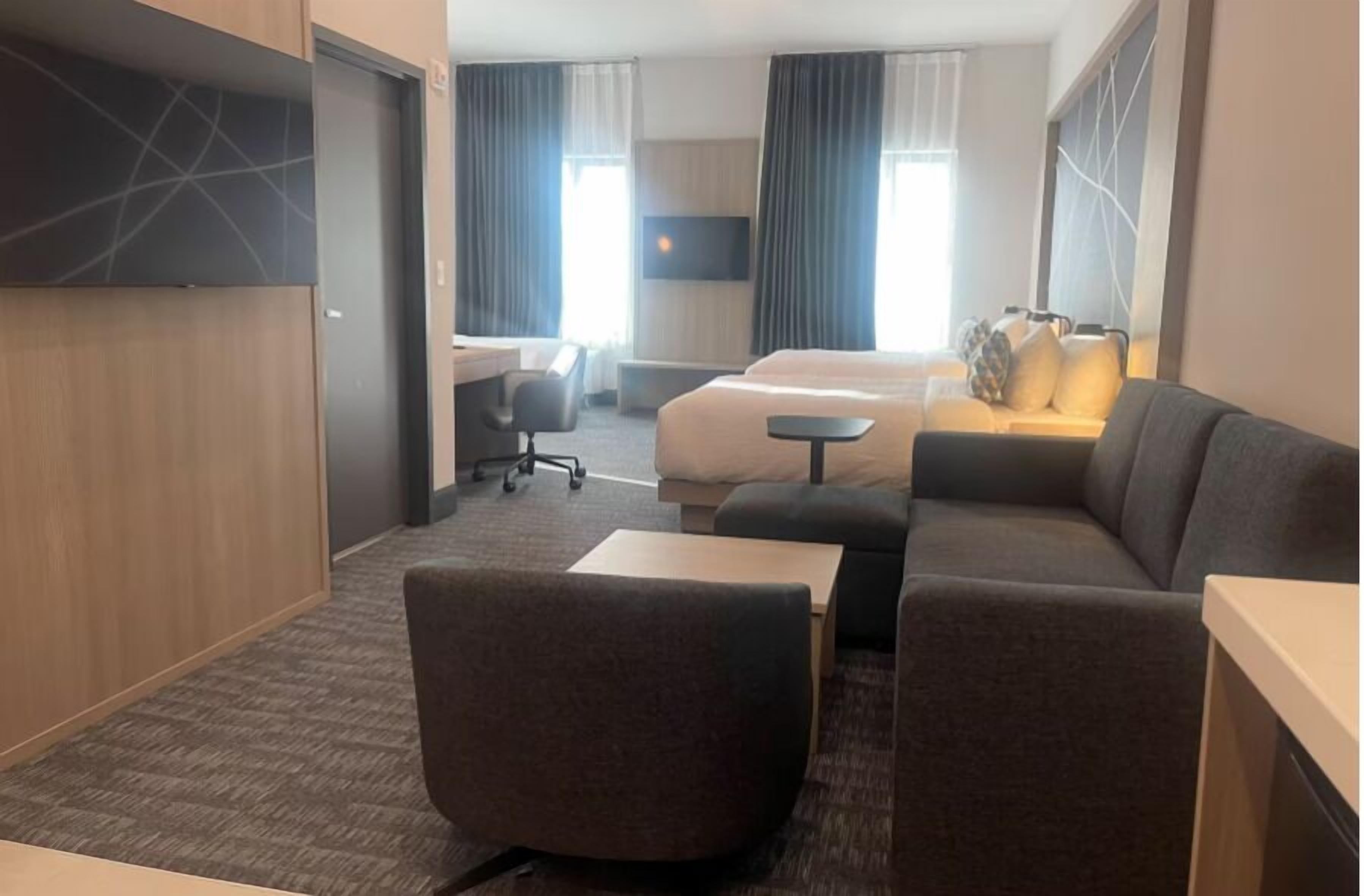 Una habitación de hotel con sofá, escritorio, cama y televisor.