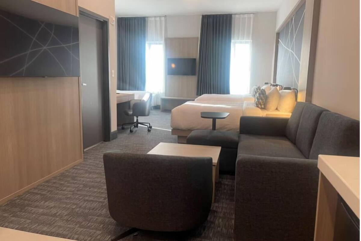 Ein Hotelzimmer mit Sofa, Schreibtisch, Bett und Fernseher.