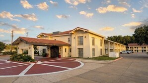 Un motel aux couleurs rouge et beige, doté d’une entrée abritée et d’un espace de stationnement.