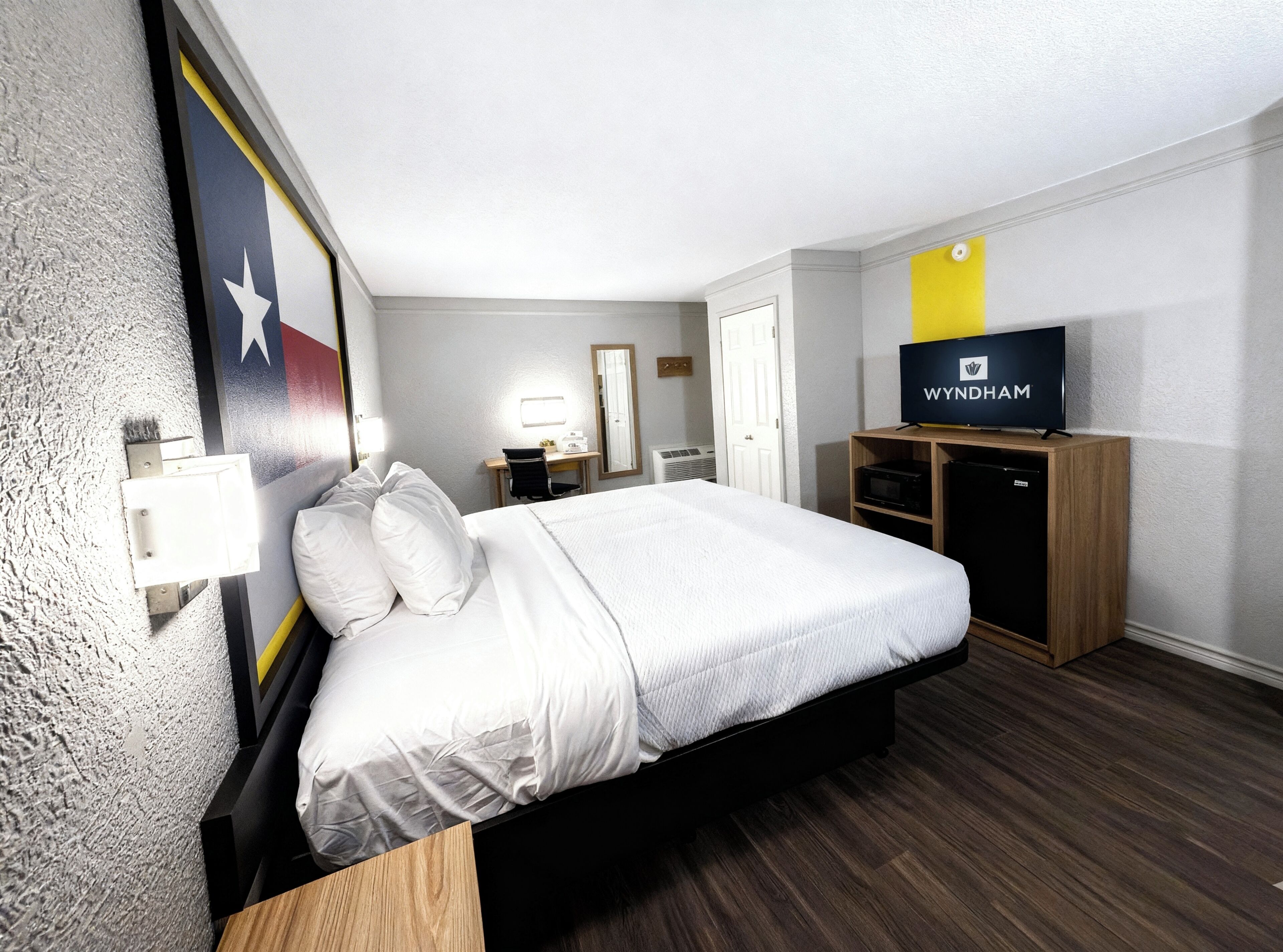 Una habitación de hotel con cama, escritorio, silla, televisor y armario.