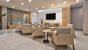 A modern lounge area with sofas, a coffee table, and a flat-screen TV mounted on the wall. - Wyndham Garden Anna (Anna)