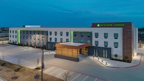 A modern hotel with a flat roof, multiple windows, and a parking lot. - Wyndham Garden Anna (Anna)