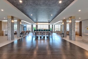 A spacious hotel lobby with a central bar area, seating arrangements, and a modern ceiling design. - Wyndham Garden Anna (Anna)