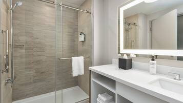A modern bathroom with a glass-enclosed shower, a white sink, and a large mirror.