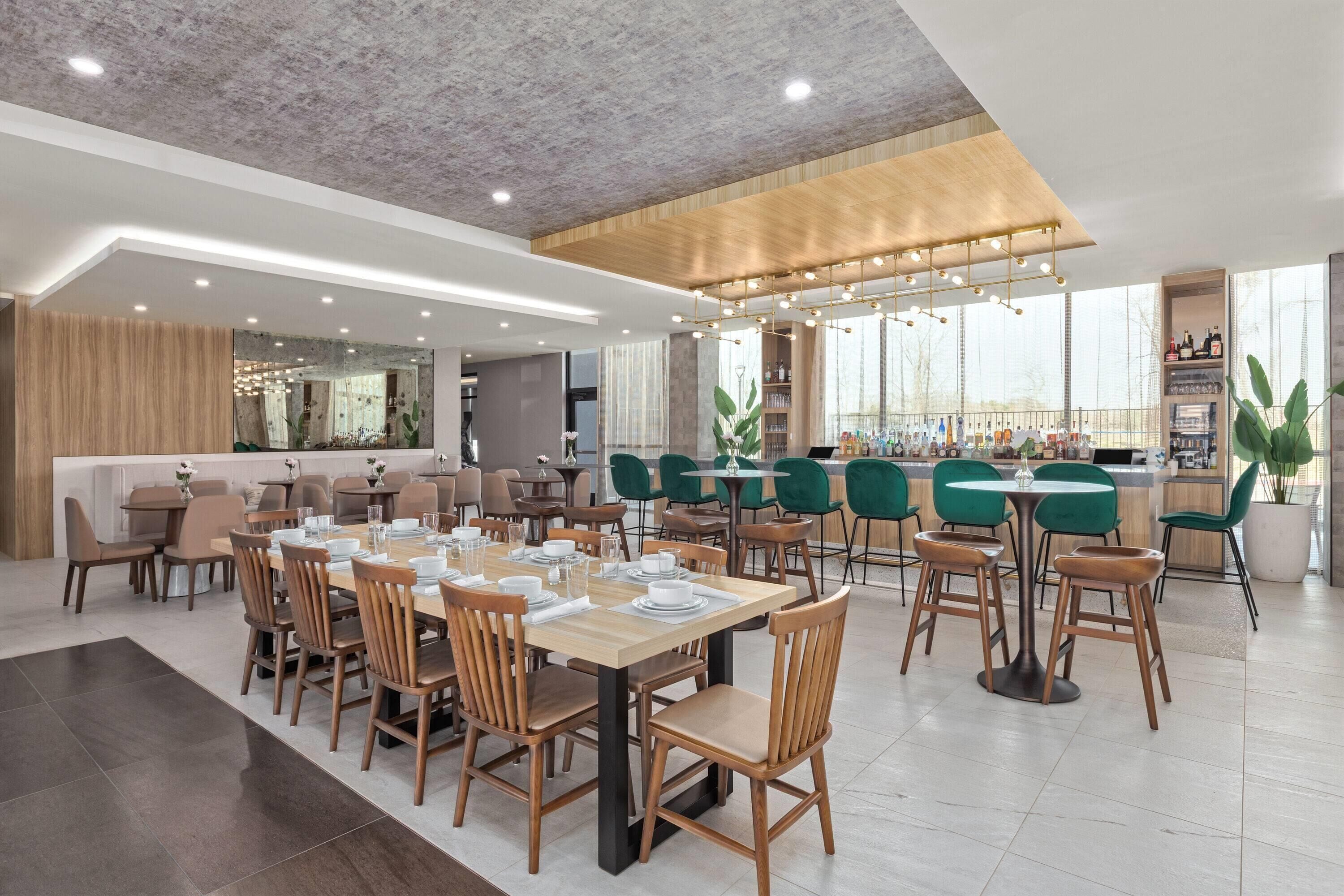 Un restaurante moderno con varias zonas de comedor, incluyendo un bar y un espacio con mesas y sillas.