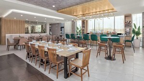 A modern restaurant with multiple dining areas, including a bar and a seating area with tables and chairs. - Wyndham Garden Anna (Anna)