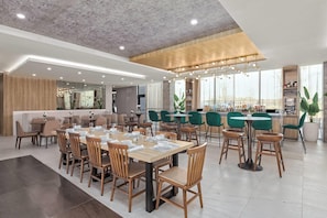 A modern restaurant with multiple dining areas, including a bar and a seating area with tables and chairs. - Wyndham Garden Anna (Anna)