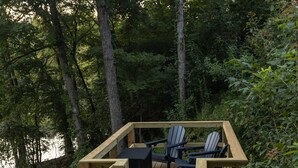 A wooden deck with a table and chairs, surrounded by trees.