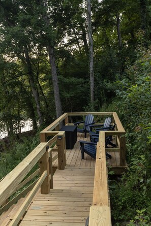 A wooden deck with a table and chairs, surrounded by trees.