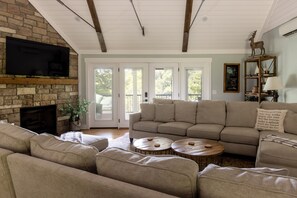 A living room with a stone fireplace, a large sofa, a television, and a wooden coffee table.