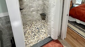 A bathroom with a shower, a tiled floor, and a visible shower curtain.
