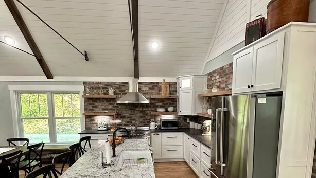 A modern kitchen with a large island, stainless steel appliances, and a brick accent wall.