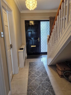 A hallway with a black door, a white staircase, and a patterned rug.