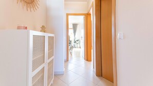 A hallway with a white cabinet, a wooden door, and a view into a dining area. - Azura Apartment with 2 Bedrooms (Conceição de Tavira)