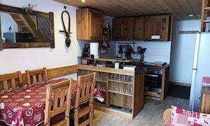 A compact kitchen with wooden cabinets, a dining table with chairs, and a refrigerator. - Superb 2-room Duplex Apartment for 6 People, Ski-in/ski-out, in the Village of Charmettoger in Arc 1800 (Bourg-Saint-Maurice)