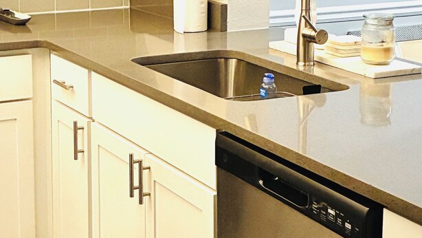 A kitchen with white cabinets, a stainless steel sink, and a dishwasher.