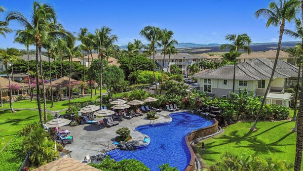 Un resort con piscina, sillas de descanso y palmeras.