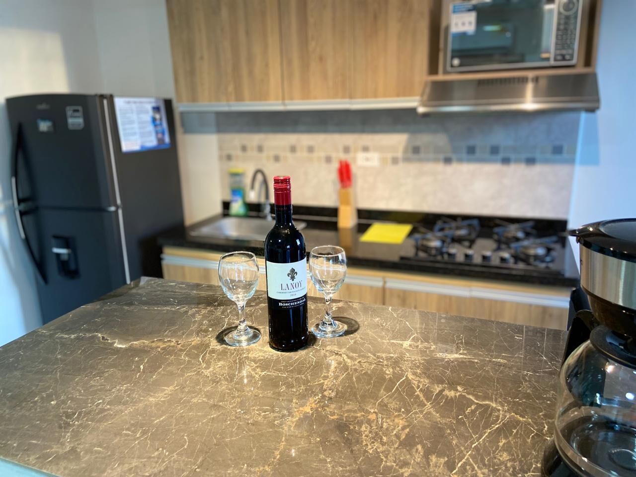 A kitchen counter with a bottle of wine and two glasses.