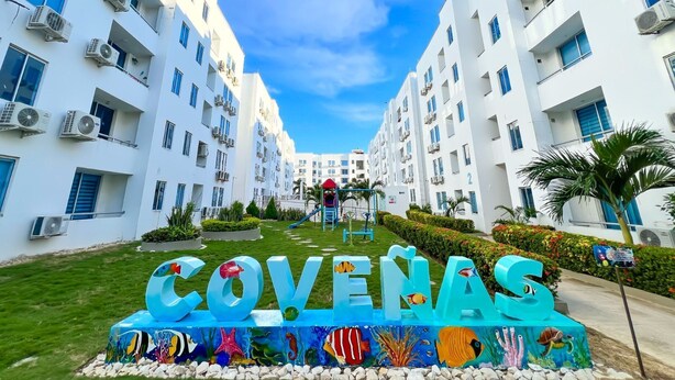A modern hotel with a central courtyard, multiple balconies, and a sign reading "COVENAS".