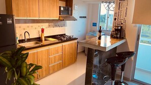 A modern kitchen with wooden cabinets, a gas stove, a microwave, and a small island with stools.