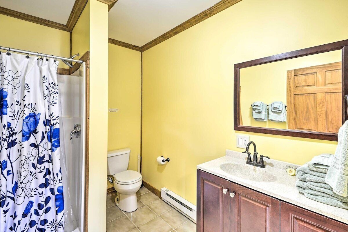 A bathroom with a shower curtain, toilet, sink, and mirror.