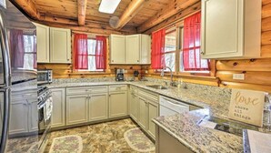 A kitchen with wooden beams, granite countertops, and a refrigerator. - Gather and Celebrate · Poconos Escape (Pleasant Mount)