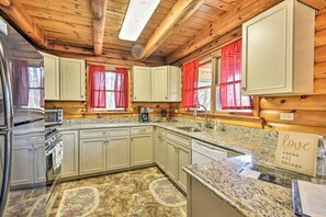 A kitchen with wooden beams, granite countertops, and a refrigerator.