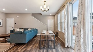 Ein modernes Wohnzimmer mit einer Couch, einem Esstisch für sechs Personen und einer Treppe zu einer weiteren Ebene.
