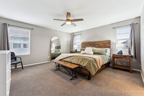 A bedroom with a bed, a desk, a chair, a ceiling fan, and a window with blinds. - Modern Spacious TownHome in Central Park (Aurora)
