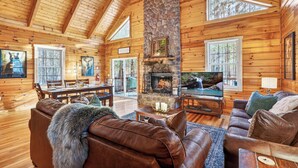 L’intérieur d’une cabane en rondins, avec une cheminée en pierre, des murs en bois et un coin salon confortable.