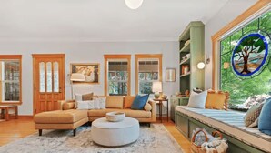 A cozy living room with a sectional sofa, ottoman, and a window seat with a view of greenery. - Luxury home in North End Boise (Boise)