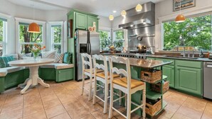 A kitchen with green cabinets, a stainless steel range hood, and a dining area with a round table and white chairs. - Luxury home in North End Boise (Boise)