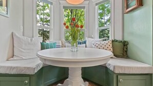 A corner seating area with a round table, green painted walls, and a window with a view of trees. - Luxury home in North End Boise (Boise)