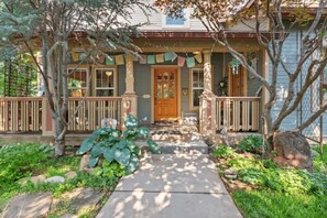 Une maison avec un porche à l’avant, une porte en bois et un chemin de pierre menant à l’entrée.